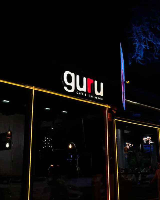 Guru Cafe & Patisserie cephesinde gece yanan ışıklı kutu harf tabela ve sarı LED hat aydınlatması