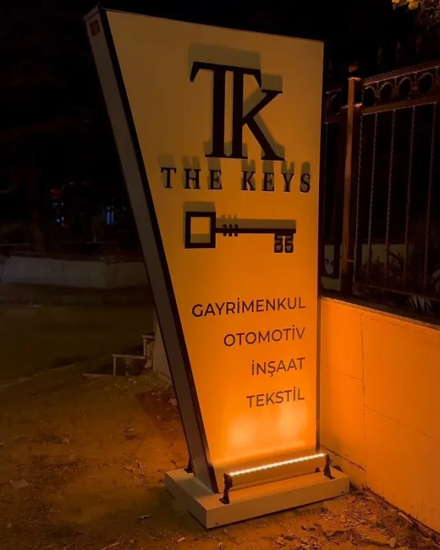 Gece aydınlatılmış The Keys totem tabelası; gayrimenkul, otomotiv, inşaat ve tekstil yazıları